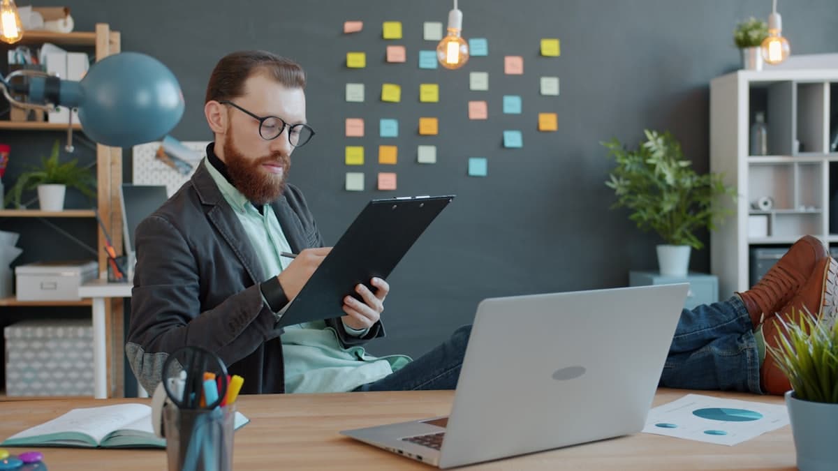 A founder working at a desk with a tablet, laptop and a wall of notes